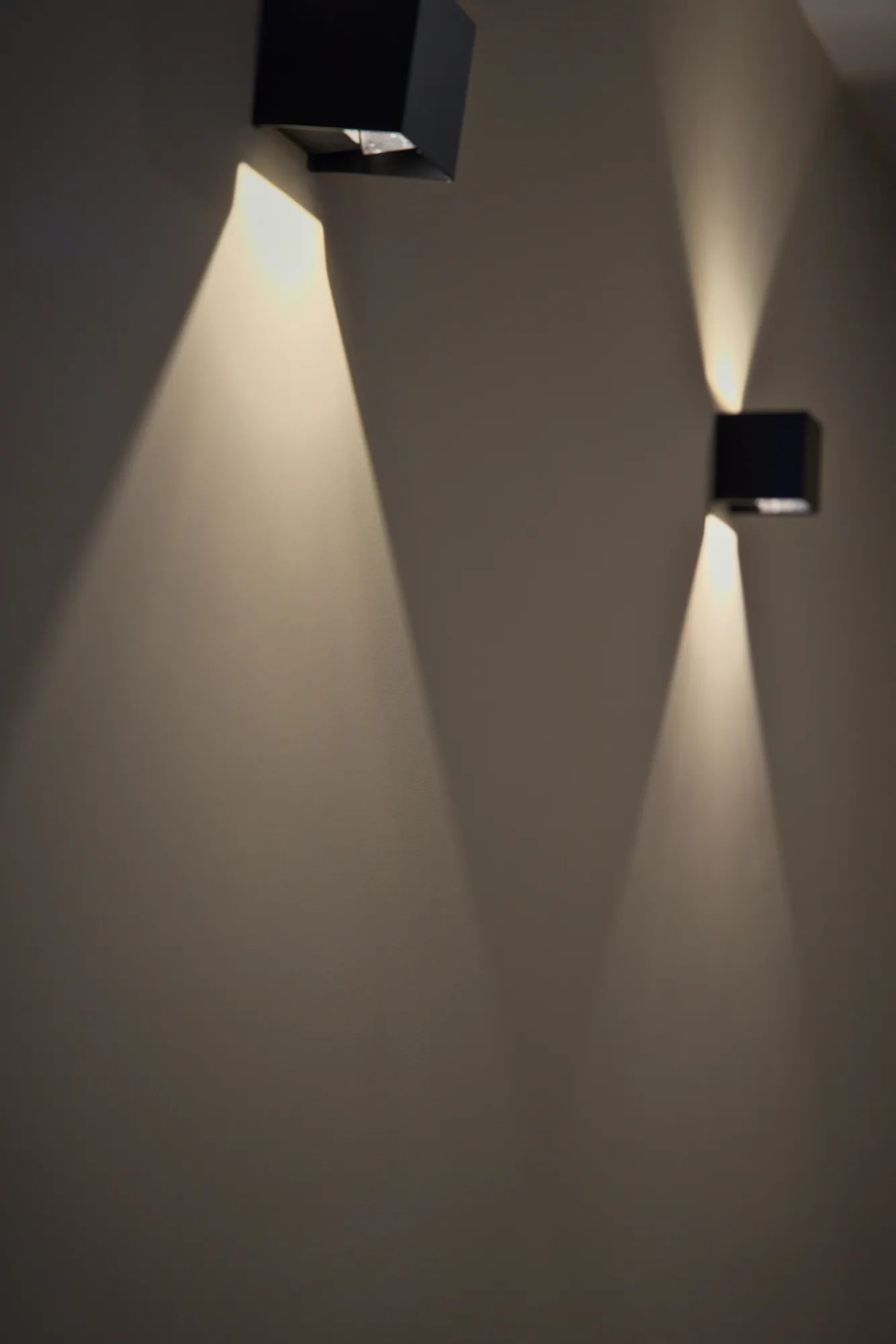 Dos apliques de pared que dibujan haces de luz cálida sobre la pared del salón