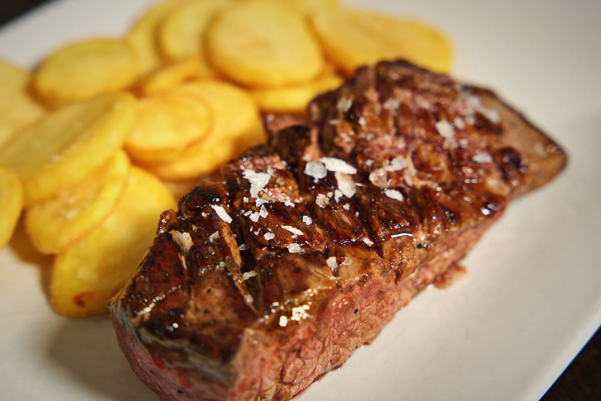 Primer plano de un bife a la parrilla con las marcas de la plancha y escamas de sal