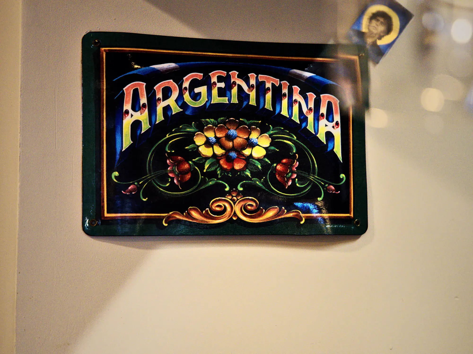 Cartel de chapa con la palabra Argentina en fileteado porteño, colgado en la pared del local