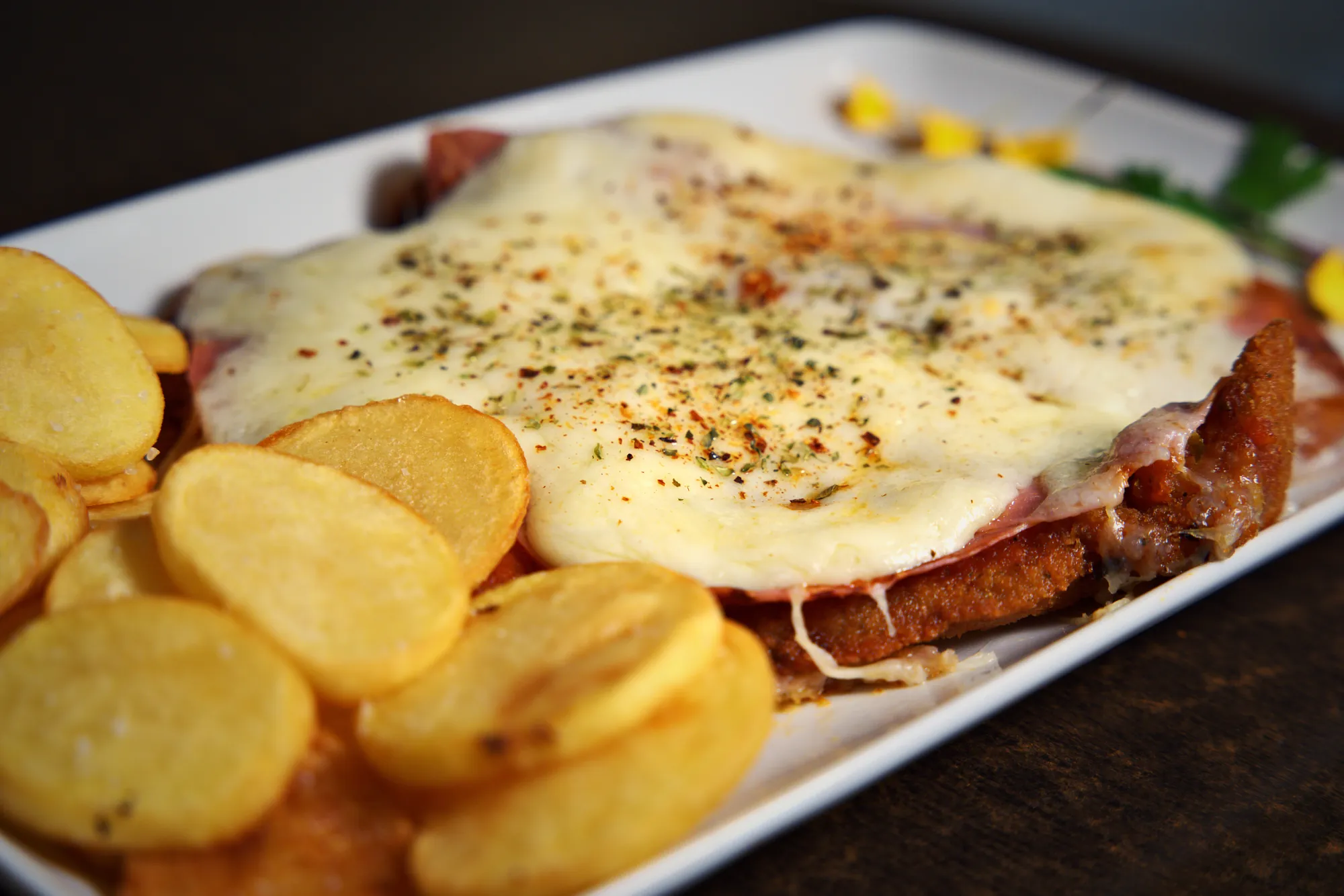 Primer plano de una milanesa napolitana con muzzarella gratinada, jamón y orégano