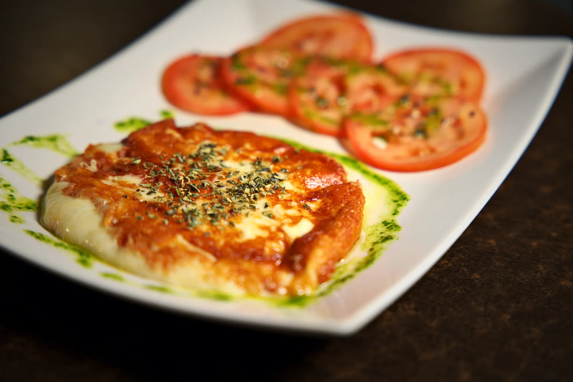 Provoleta dorada con orégano, chimichurri y rodajas de tomate